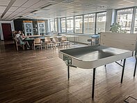 Großer Raum, modern eingerichtet mit Tischen und 2 Telefonzellen
