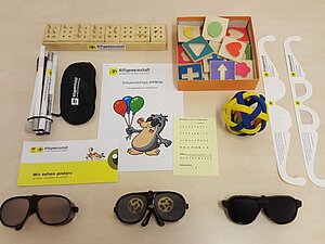 Lernbox für die AM4Kids-Workshops an verschiedenen Wiener Schulen AM4Kids-Lernbox bestehend aus Langstock, Augenbinden, Simulationsbrillen, Braille-Alphabet und haptischen Holzbausteinen