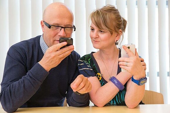 Mitarbeiter zeigt einer Frau die Anwendungen bei einem Smartphone.